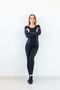 Portrait of young woman standing against wall