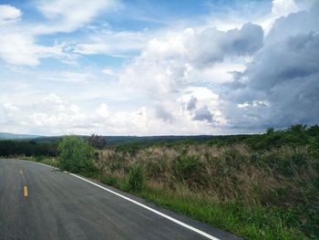 Road amidst field against sky