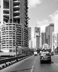 Cars on road by buildings against sky