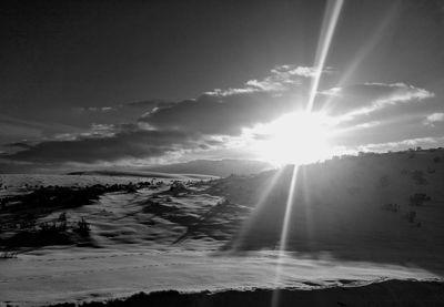 Sunlight streaming through clouds over landscape