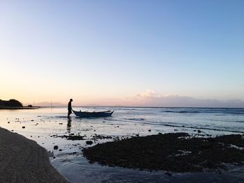 Silhouette man on beach against sky during sunset