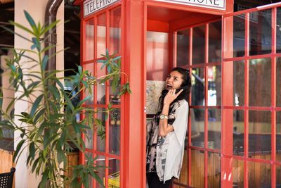 Woman talking on telephone while standing in booth