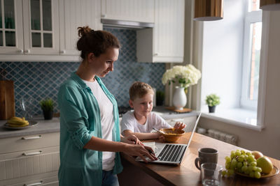 Smart mother doing freelance job near son