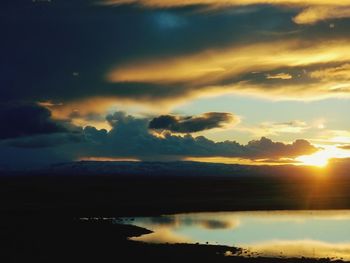 Scenic view of dramatic sky over lake during sunset