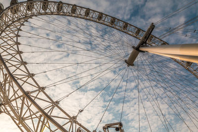 Low angle view of ferris wheel against cloudy sky