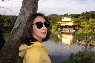 Portrait of young woman in sunglasses against lake