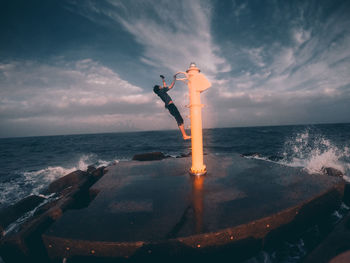 Rear view of a man jumping against calm sea