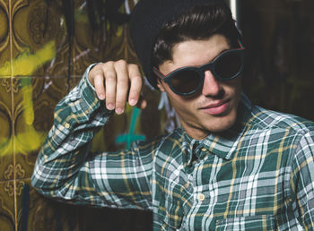 Young man wearing sunglasses standing by wall