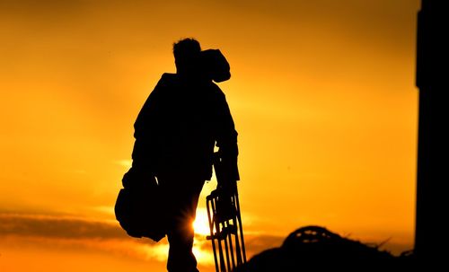 Silhouette man standing against sky during sunset