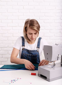 Woman looking at camera on table against wall