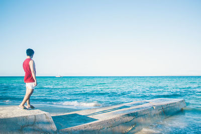 Rear view of man looking at sea against sky