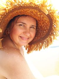 Portrait of smiling young woman wearing hat at beach