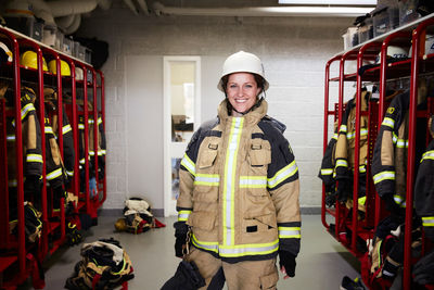 Portrait of smiling female firefighter standing in locker room at fire station