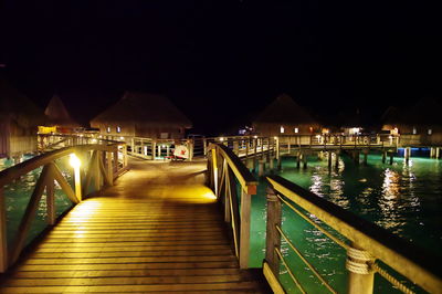 Illuminated bridge over river against sky at night