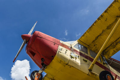 Low angle view of vintage airplane against blue sky