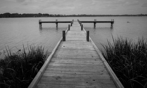 Wooden pier over lake against sky