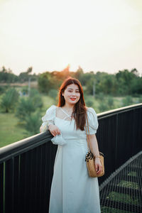 Young woman standing against railing