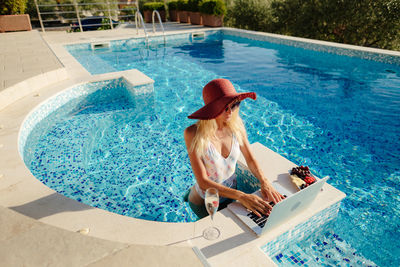 Woman using laptop in swimming pool