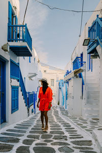 Rear view of man walking on alley amidst buildings