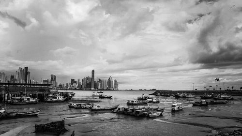 Boats moored at dock against cloudy sky