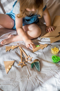 High angle view of girl playing with decoration while sitting on bed