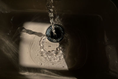 Bathroom sink wet from tap water, low light, water reflections, and drops