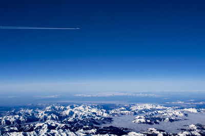 Aerial view of snowcapped landscape against blue sky