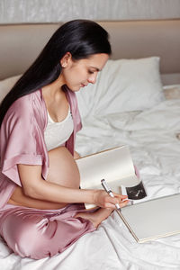 Portrait of young woman sitting on bed at home