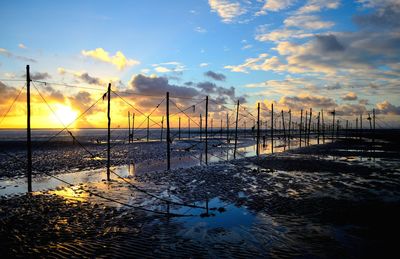 Fish traps at beach against sky sunrise