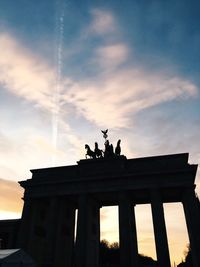 Low angle view of silhouette statue against cloudy sky