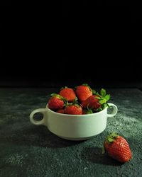 Close-up of strawberries in bowl against black background