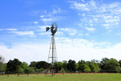 Low angle view of windmill on field against sky