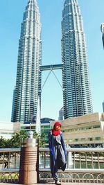 Low angle view of man standing by skyscraper against clear sky