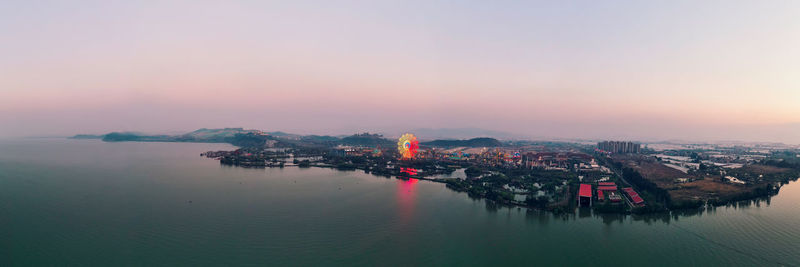 High angle view of buildings by sea against sky at sunset