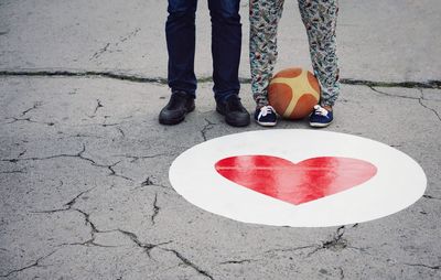Low section of people standing by heart shape on footpath at playground