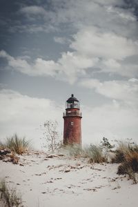 Lighthouse on beach against sky during winter