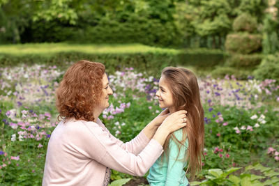 Side view of young woman standing against trees