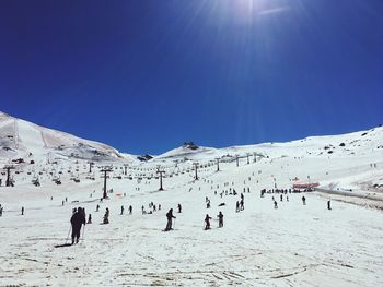 Group of people on snowcapped mountain against sky