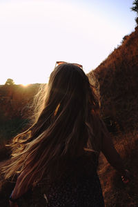 Rear view of woman standing on mountain against sky