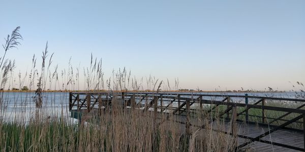 Pier over lake against clear sky