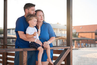 Father and daughter sitting on railing