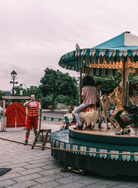 People at amusement park against sky