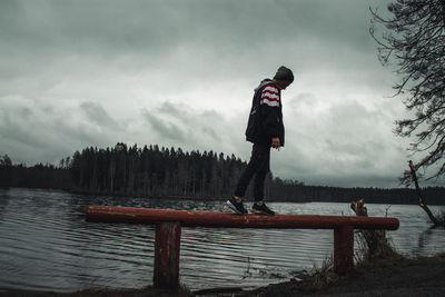 Man standing by lake against sky during winter