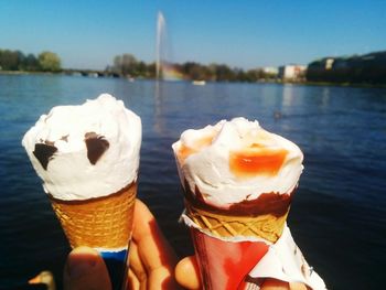 Close-up of hand holding ice cream against sky