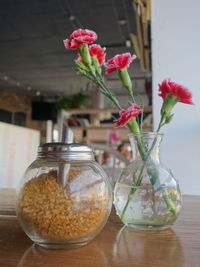 Brown sugar in container by flower vase on table in restaurant