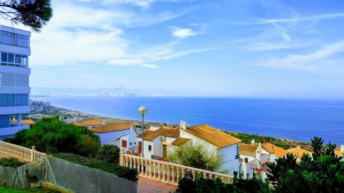 Scenic view of sea by buildings against sky