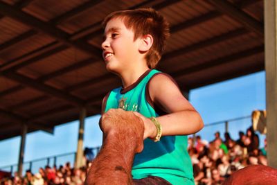 Low angle view of smiling boy at bleachers