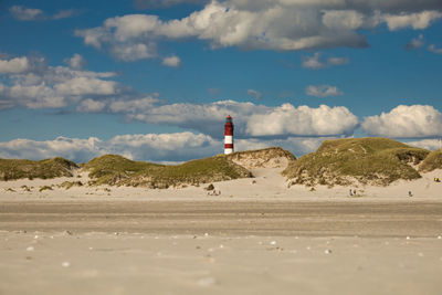 Lighthouse on beach against sky