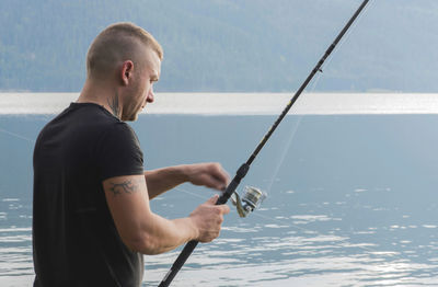Man holding fishing rod by lake