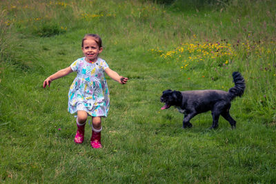 Full length of girl with dog on grass at park